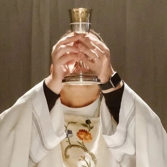 priest standing with communion cup